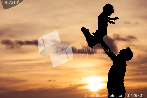 Image of Father and son playing on the beach at the sunset time.