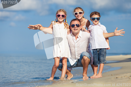 Image of Father and children playing on the beach at the day time.