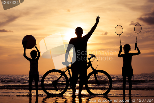 Image of Father and children playing on the beach at the sunset time.