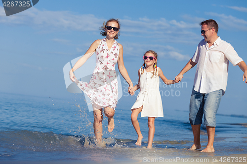 Image of Happy family walking on the beach at the day time.