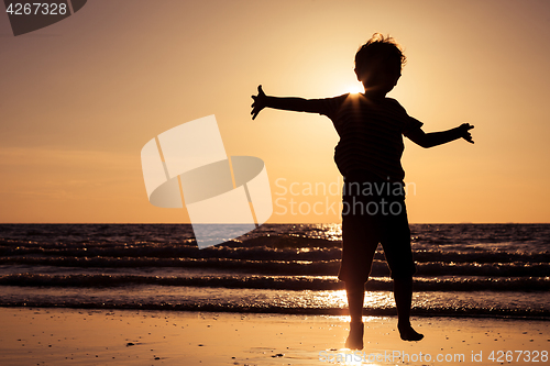 Image of Happy little boy running on the beach