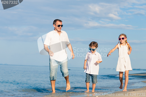 Image of Father and children playing on the beach at the day time.