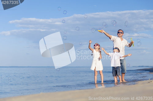 Image of Father and children playing on the beach at the day time.