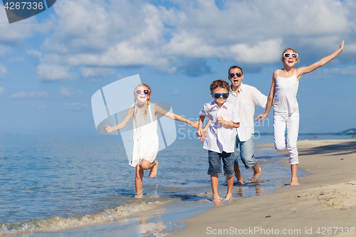 Image of Father and children playing on the beach at the day time.