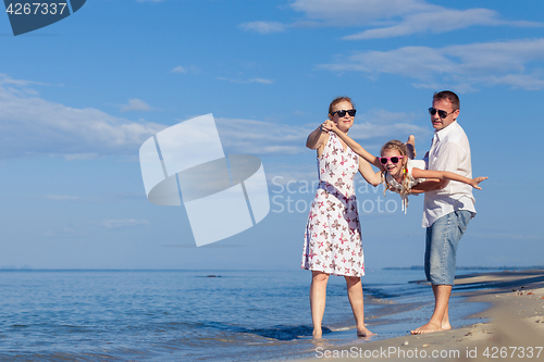 Image of Happy family walking on the beach at the day time.