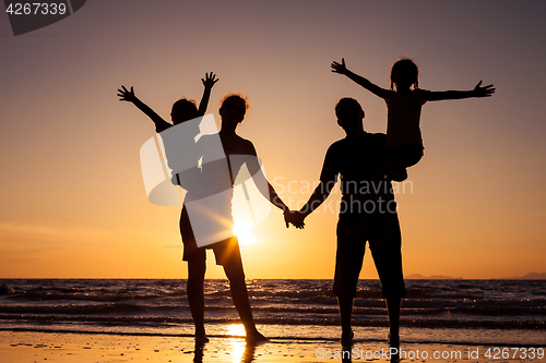 Image of Silhouette of happy family who playing on the beach at the sunse