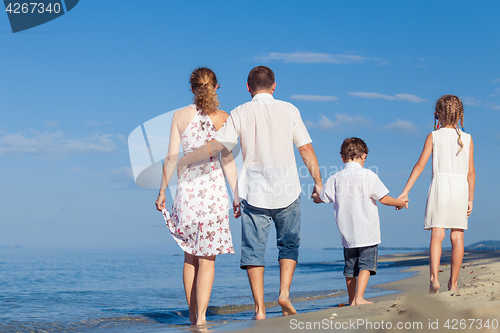 Image of Happy family walking on the beach at the day time.