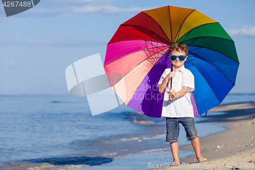 Image of Little boy with umbrella standing on the beach