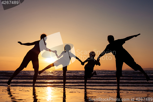 Image of Silhouette of happy family who playing on the beach at the sunse