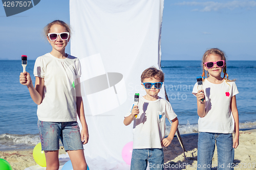 Image of Two sisters and brother playing on the beach at the day time.