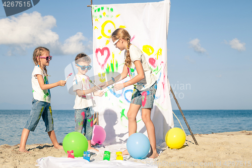 Image of Two sisters and brother playing on the beach at the day time.