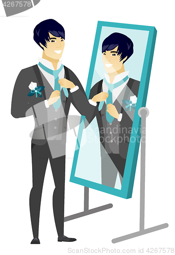 Image of Groom looking in the mirror and adjusting tie.