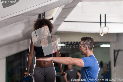 Image of black woman doing parallel bars Exercise with trainer