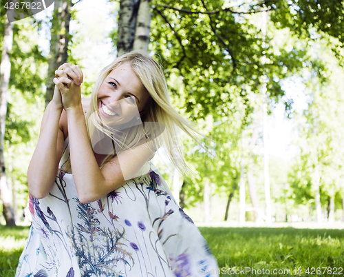 Image of happy blond young woman in park smiling