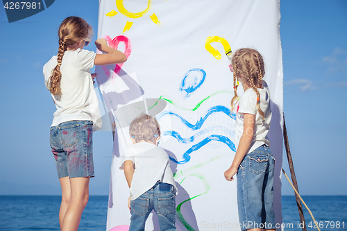 Image of Two sisters and brother playing on the beach at the day time.