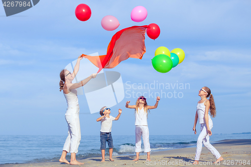 Image of Mother and children playing on the beach at the day time.