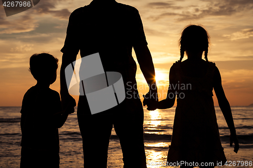 Image of Father and children playing on the beach at the sunset time.