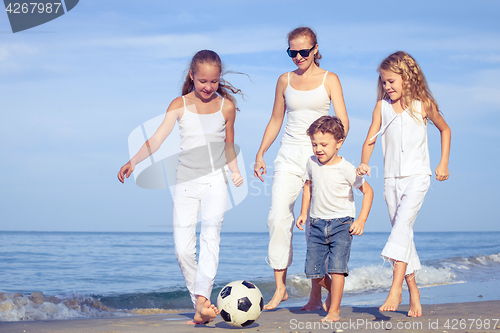 Image of Mother and children playing on the beach at the day time.