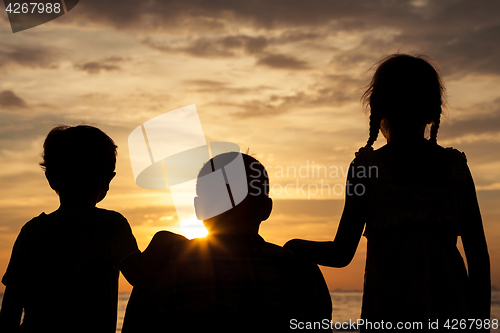 Image of Father and children playing on the beach at the sunset time.