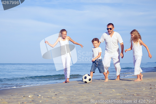 Image of Father and children playing on the beach at the day time.