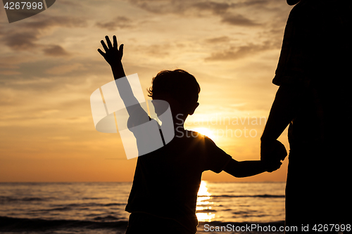 Image of Father and son playing on the beach at the sunset time.