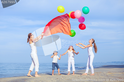 Image of Mother and children playing on the beach at the day time.