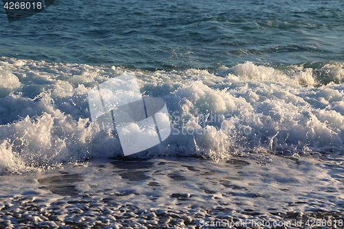 Image of Sea waves and white foam on the evening coast