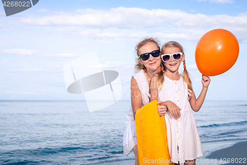 Image of Mother and daughter playing with balloons on the beach at the da