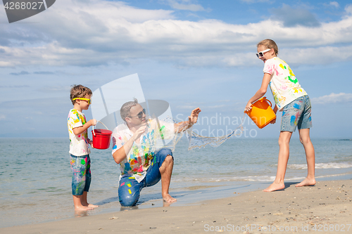 Image of Father and children playing on the beach at the day time.