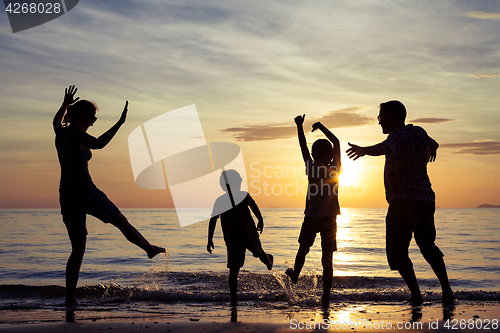 Image of Silhouette of happy family who playing on the beach at the sunse