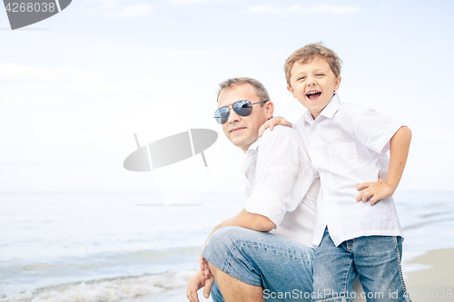 Image of Father and son playing on the beach at the day time.