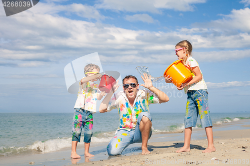 Image of Father and children playing on the beach at the day time.