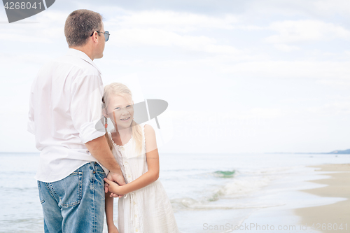 Image of Father and daughter playing on the beach at the day time.