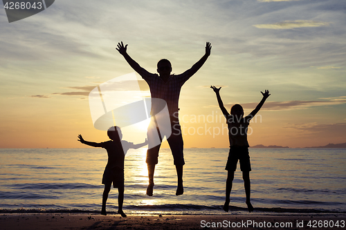 Image of Father and children playing on the beach at the sunset time.