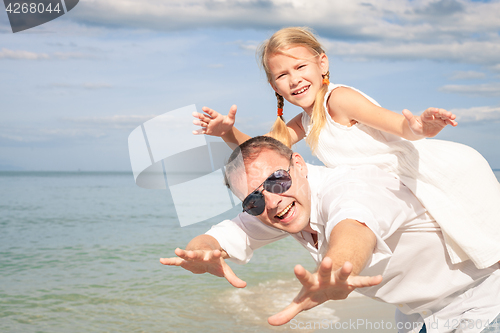 Image of Father and daughter playing on the beach at the day time.