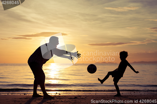 Image of Father and son playing on the beach at the sunset time.