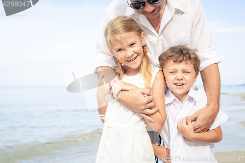 Image of Father and children playing on the beach at the day time.