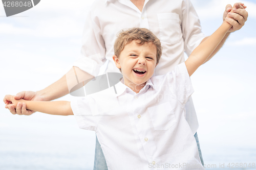 Image of Father and son playing on the beach at the day time.