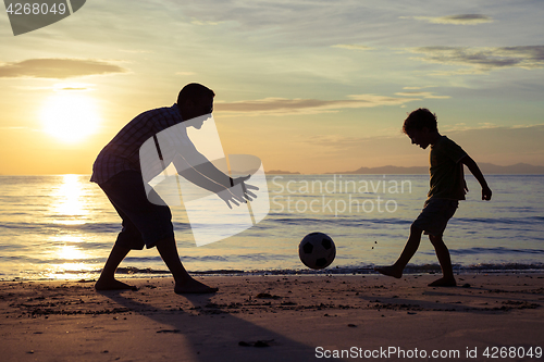 Image of Father and son playing on the beach at the sunset time.