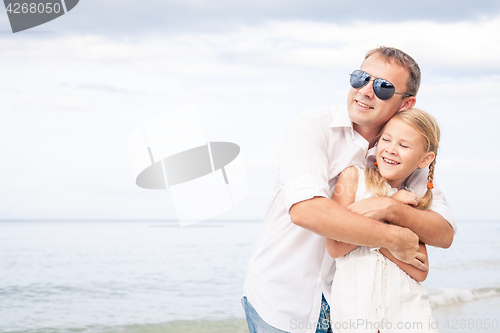 Image of Father and daughter playing on the beach at the day time.