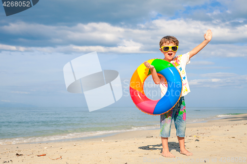 Image of Little boy with rubber ring standing on the beach