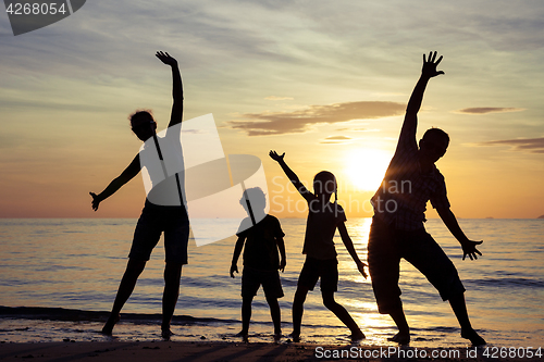 Image of Silhouette of happy family who playing on the beach at the sunse