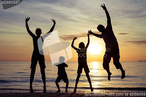 Image of Silhouette of happy family who playing on the beach at the sunse