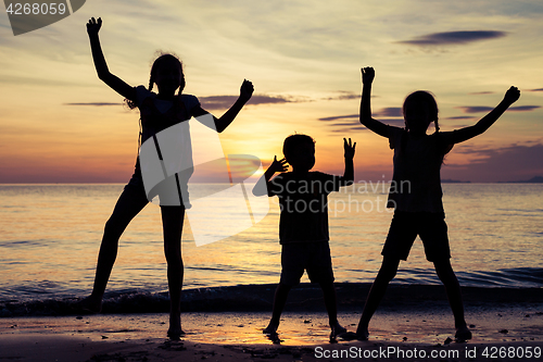 Image of Happy children playing on the beach at the sunset time.