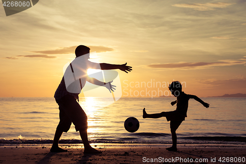 Image of Father and son playing on the beach at the sunset time.