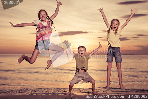 Image of Happy children playing on the beach at the sunset time.