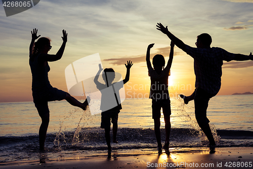 Image of Silhouette of happy family who playing on the beach at the sunse