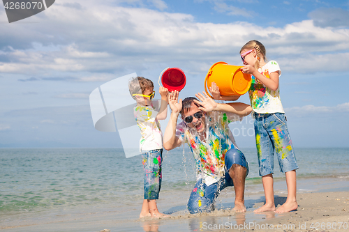 Image of Father and children playing on the beach at the day time.