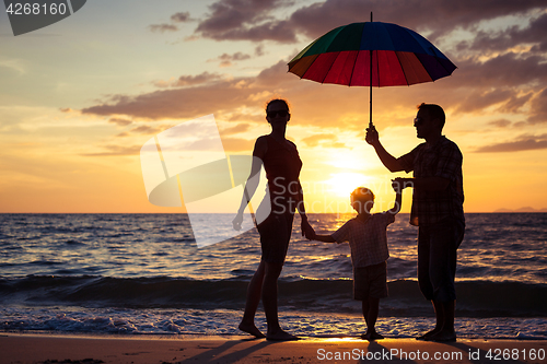 Image of Silhouette of happy family who playing on the beach at the sunse