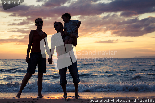 Image of Silhouette of happy family who playing on the beach at the sunse